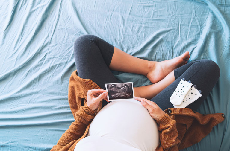 Gravid kvinne ser på bilde fra ultralyd