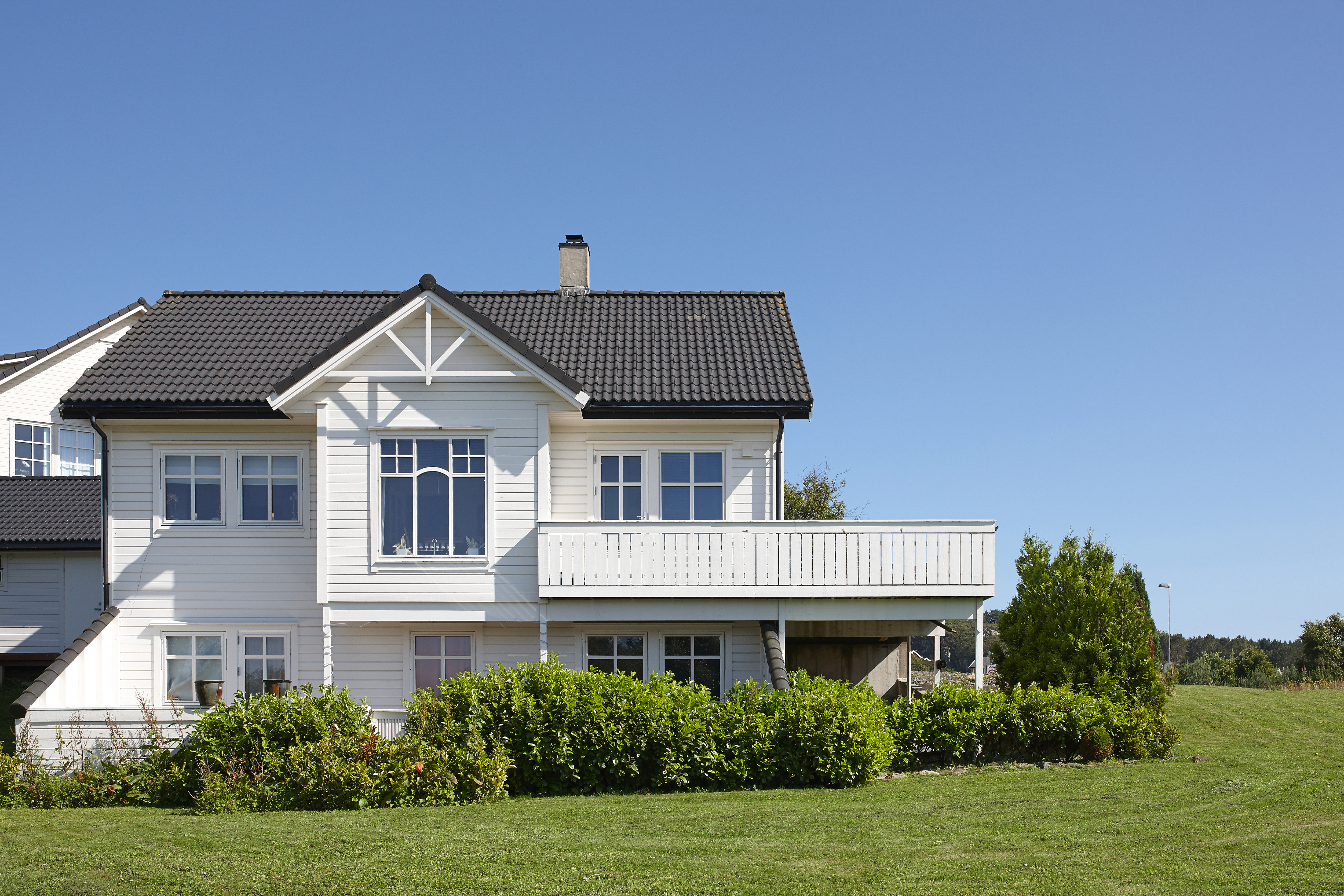 Hvitt hus i frodig hage på en solskinnsdag